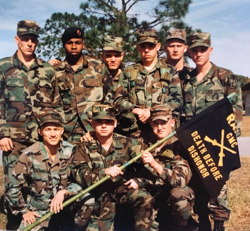 Eight soldiers in U.S. Army woodland camouflage in two rows outdoors, the front row holding the black crossed-rifles Ranger flag reading Death Before Dishonor
