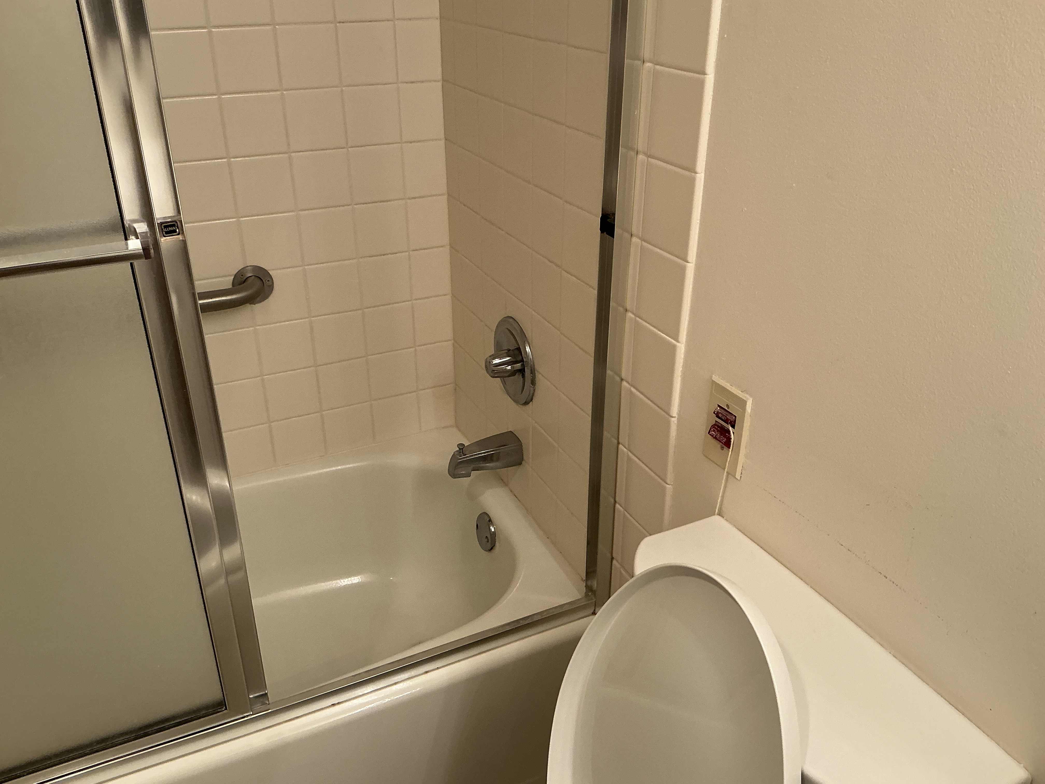 Original accessible bath — tub with sliding glass door, grab bar and pull-cord alarm, before work began