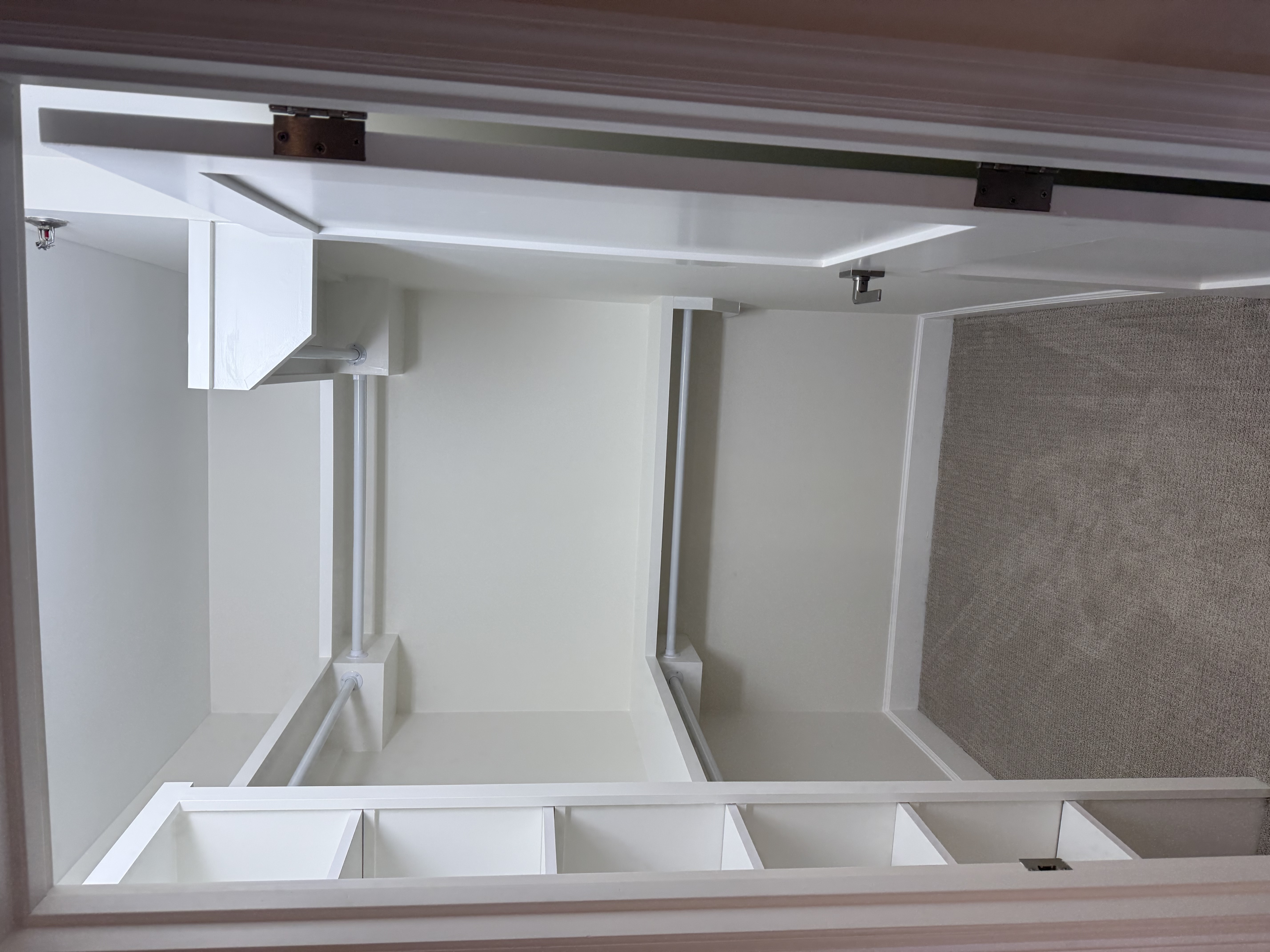 Finished closet built-ins seen from the doorway — white wire-and-wood shelving along the left wall and white corner shelves with hanging rods, the open door visible on the right