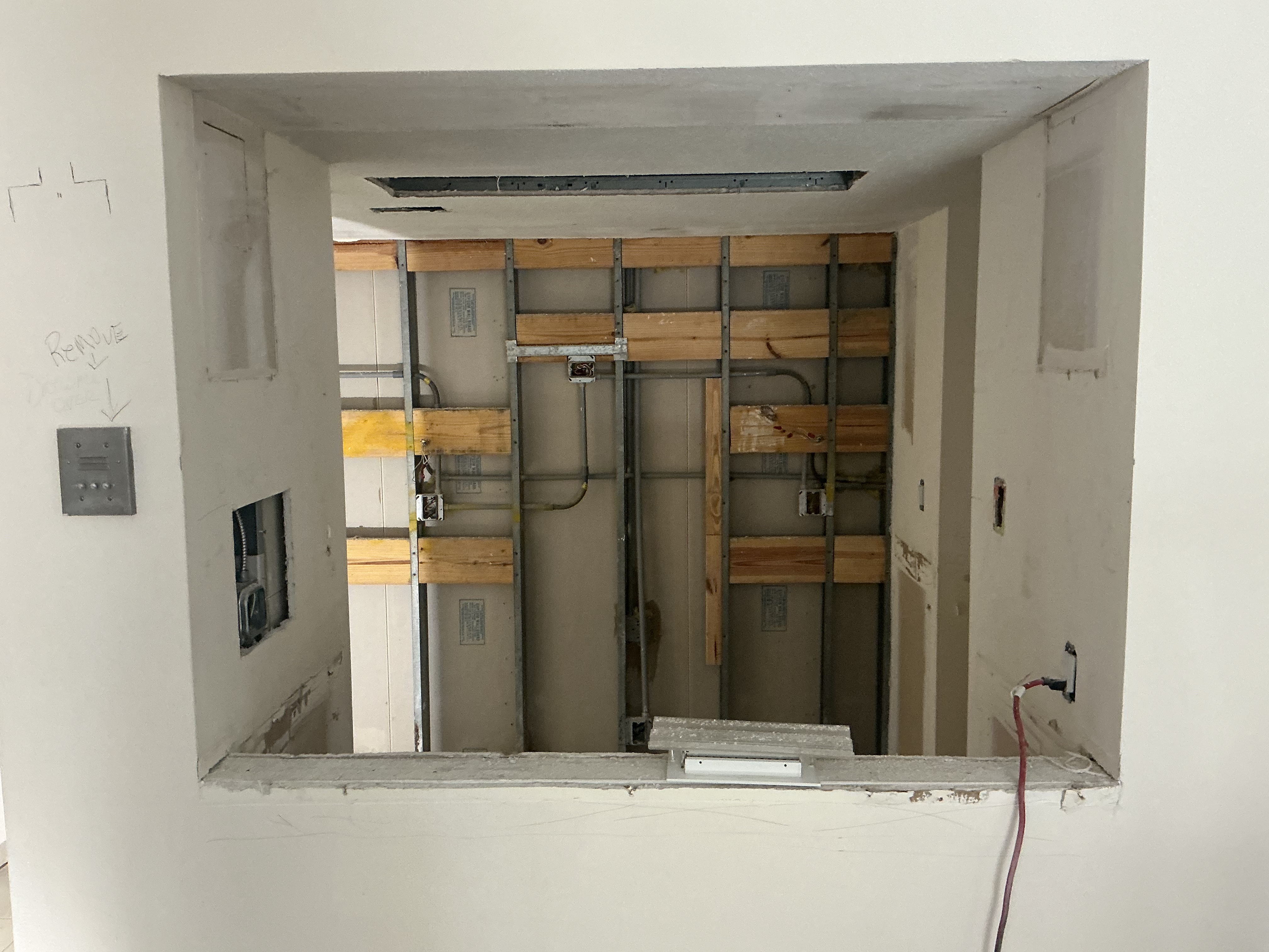 Kitchen walls opened up mid-renovation — metal studs, blocking, conduit and junction boxes exposed