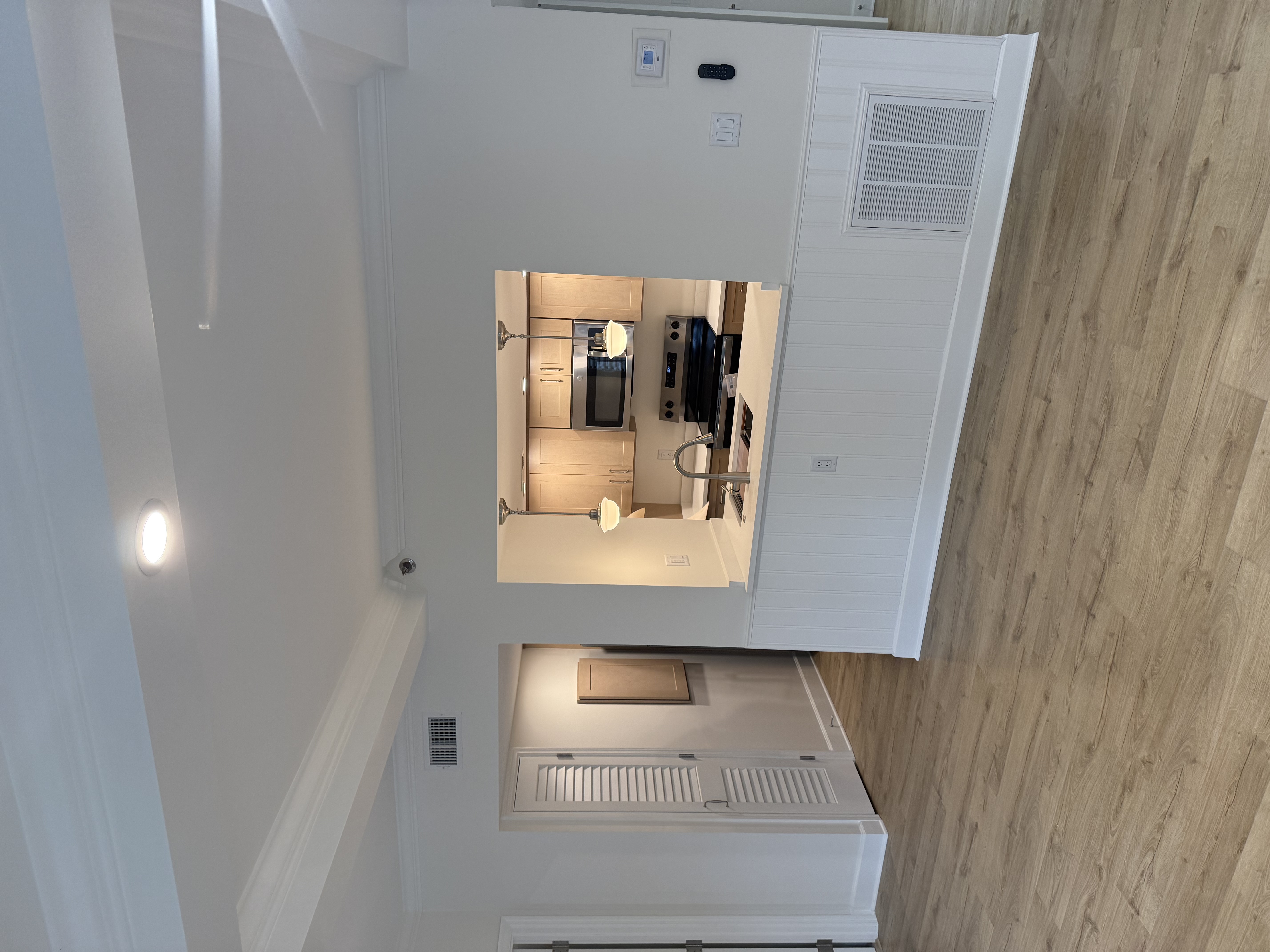 Finished kitchen seen through the pass-through — shaker cabinets, quartz counters, pendant lights
