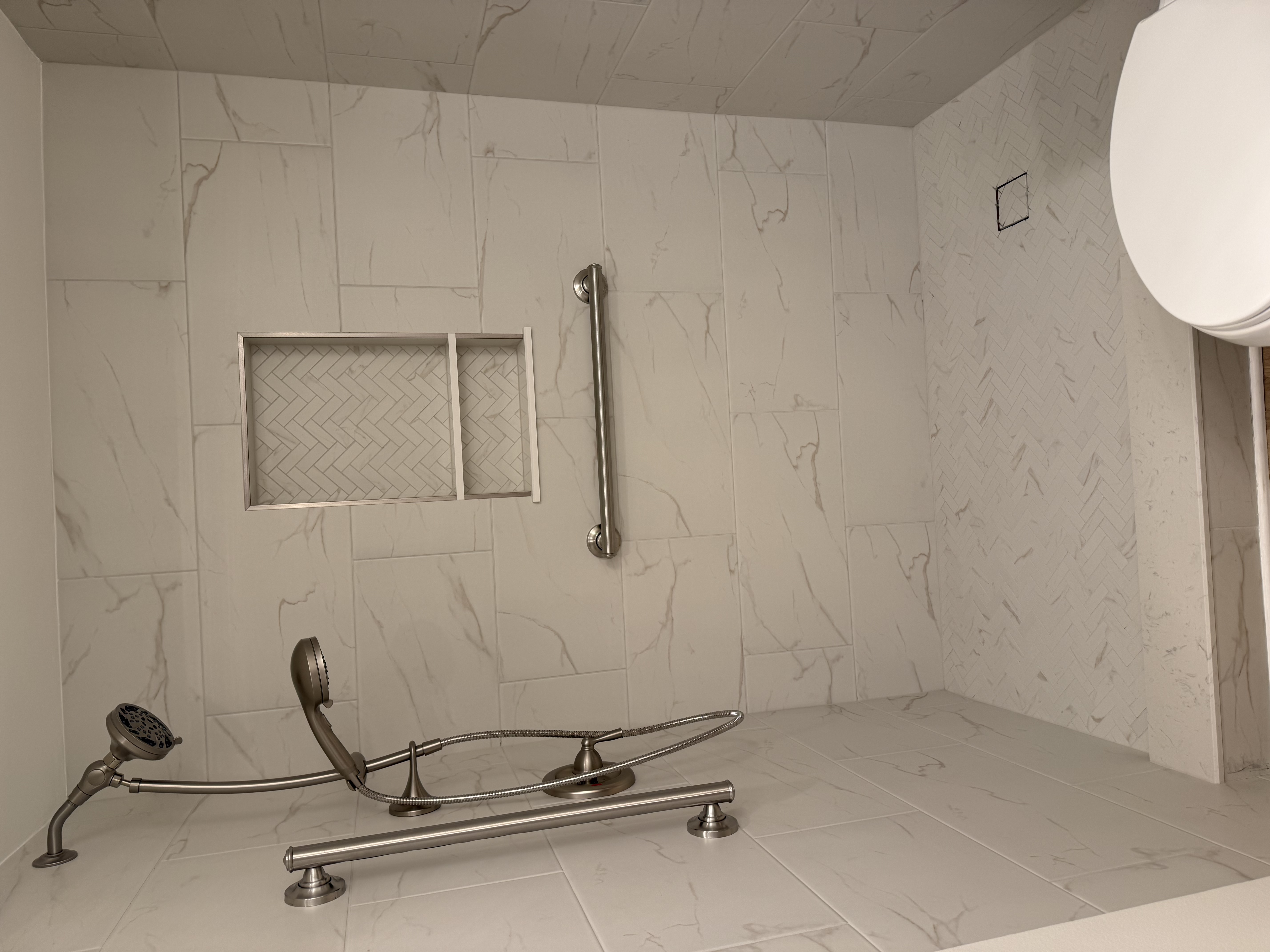 Finished accessible bath — curbless marble walk-in shower with herringbone mosaic floor and brushed nickel fixtures
