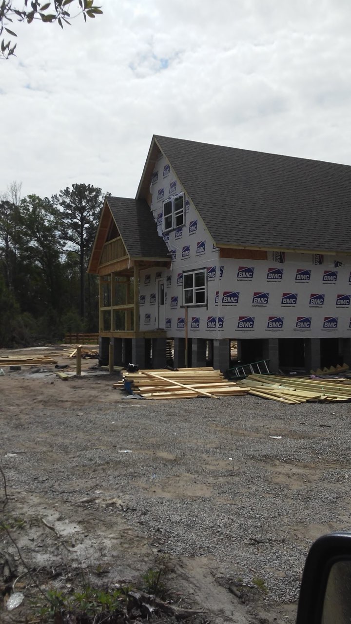 Raised Low Country home framed and wrapped, standing on its piers over the lot