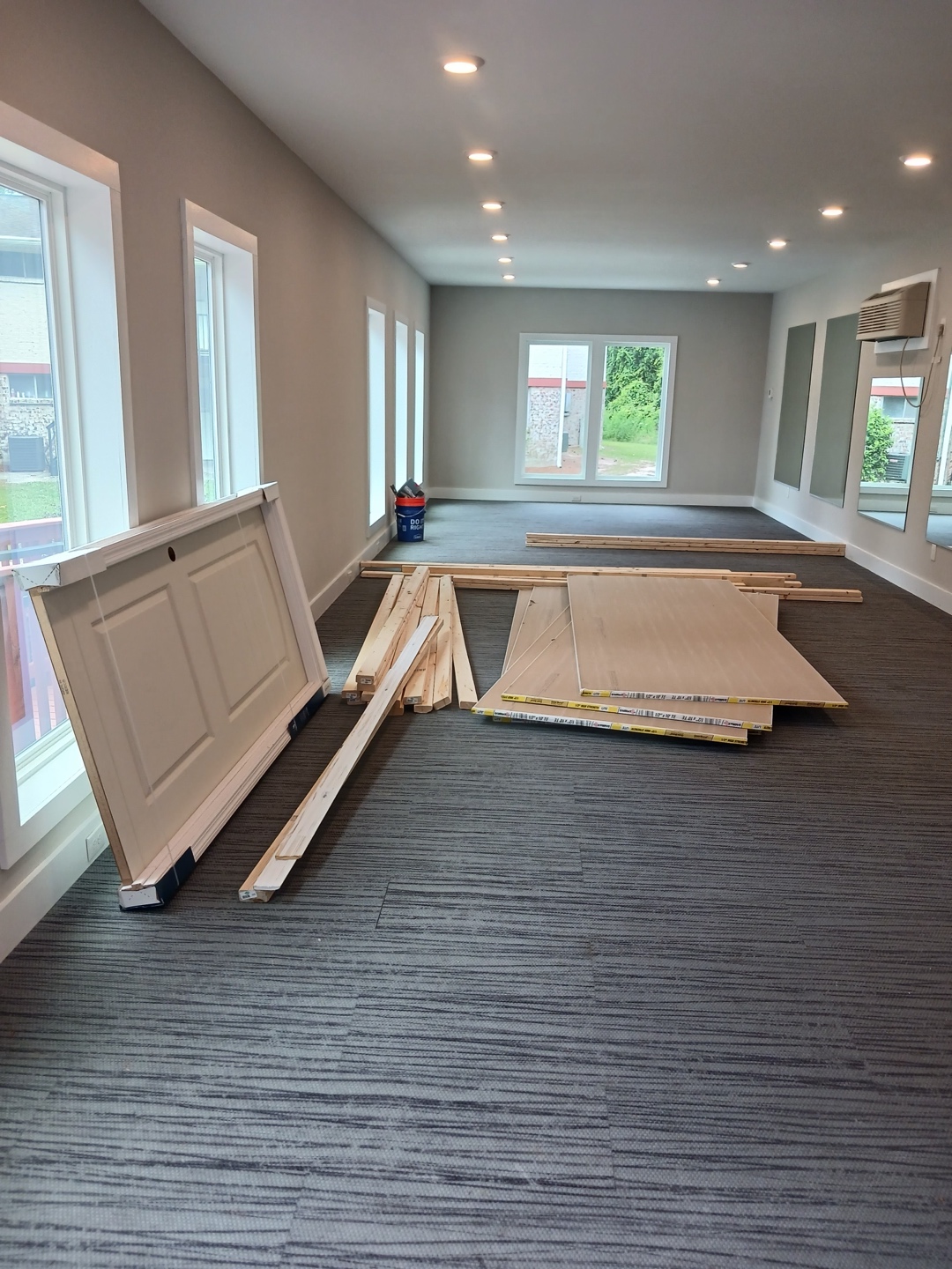Tenant improvements in the same building — the office mid fit-out, with a new door, flooring planks and trim staged on the carpet while the room is finished out